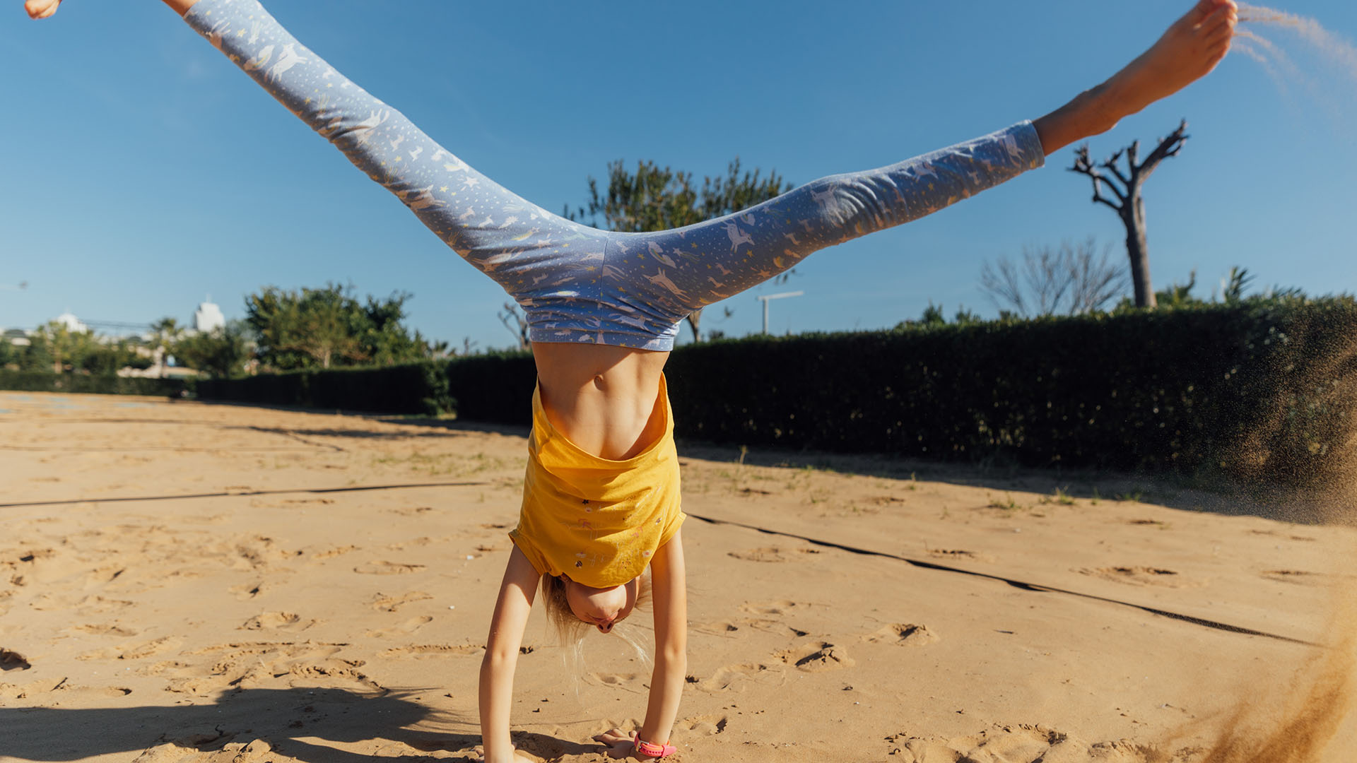 person does handstand on sand