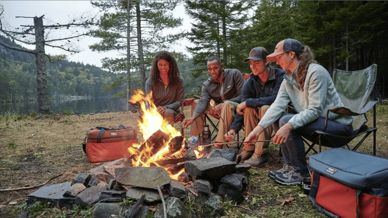 A group photo of people making s'mores while camping.