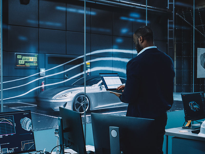 Man looking at a computer while performing tests on a vehicle