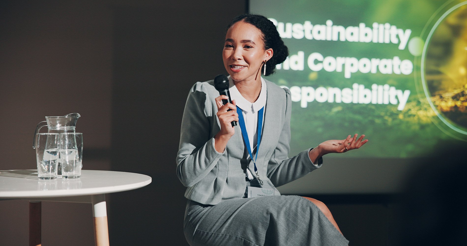 a woman in a suit speaking at a conference
