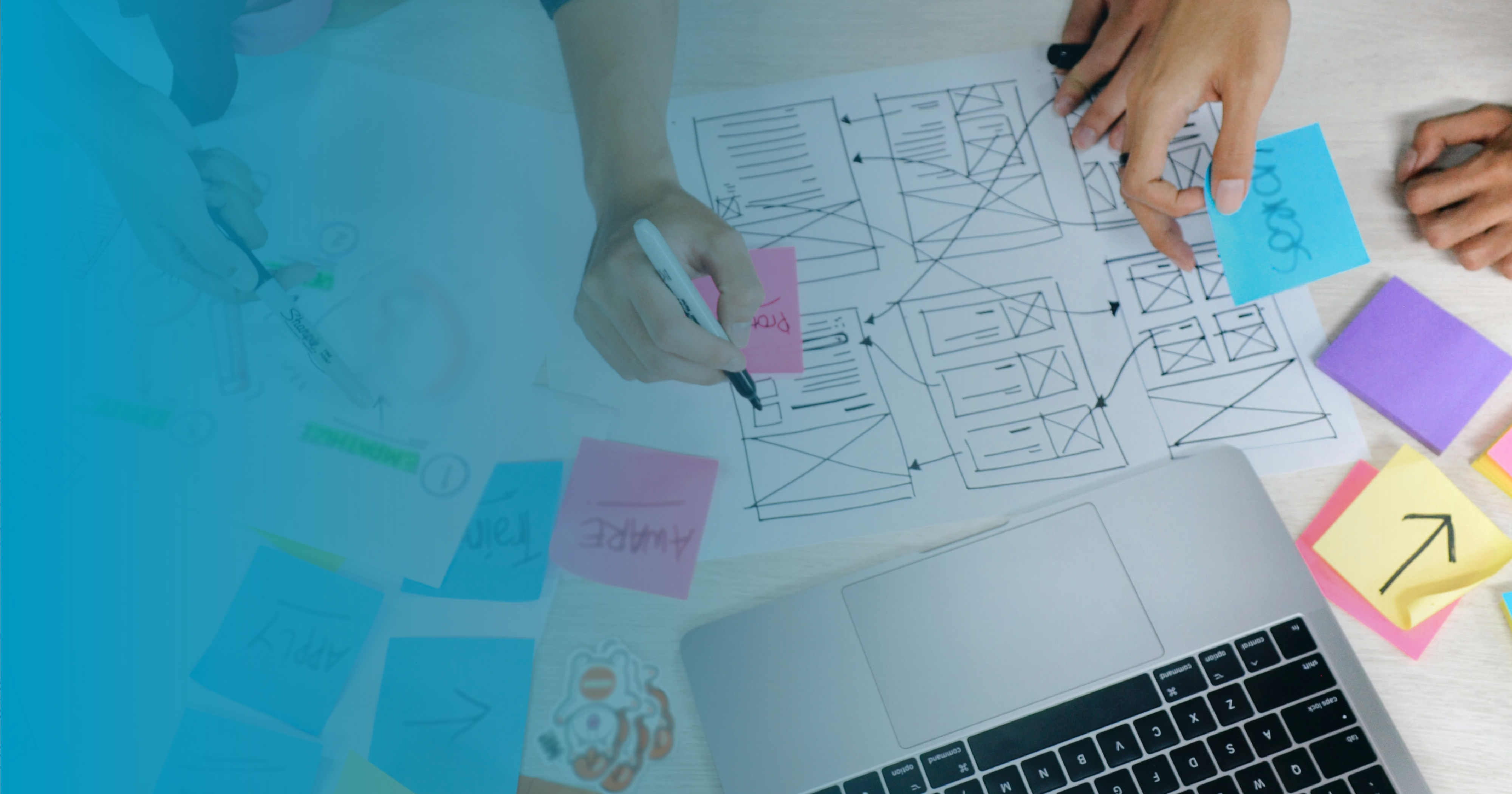 Photo from above of three people sketching a web page design on paper and colorful sticky notes
