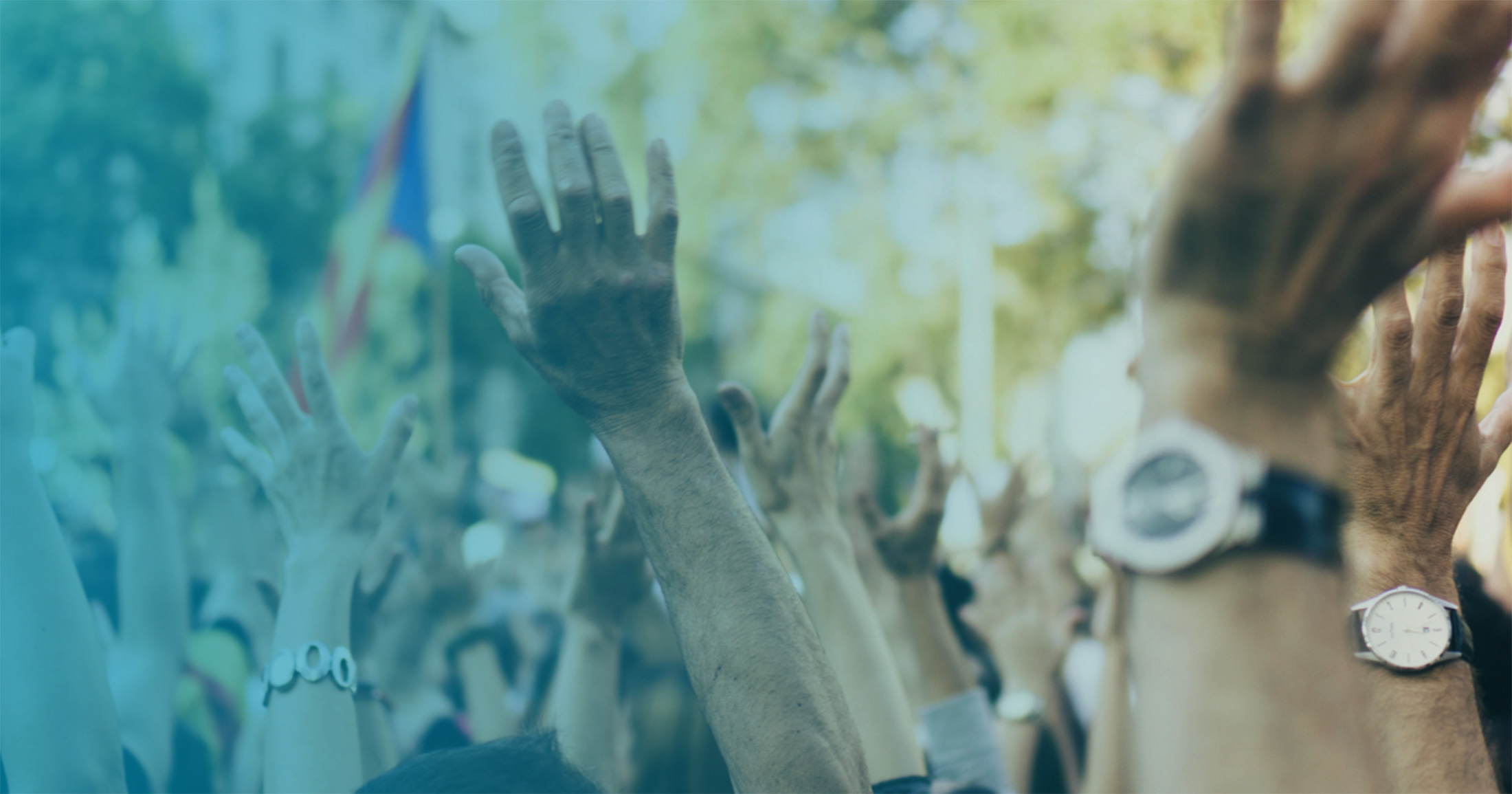 Large group of people raising hands at a rally