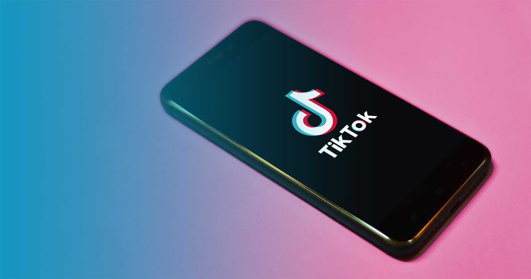 Phone with TikTok app open on a pink background