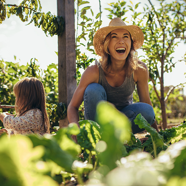 A woman laughs while sitting in a garden with a small girl