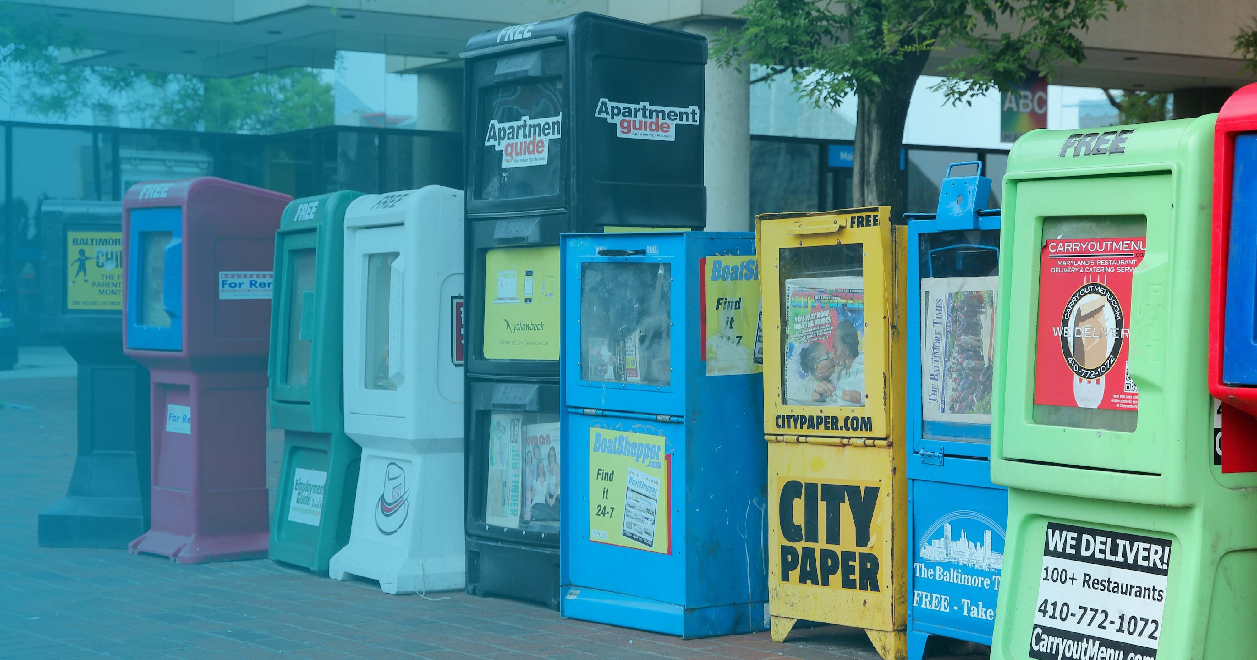 A line of colorful newsracks on a city street