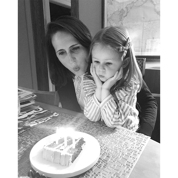 Ashley and her daughter blowing out candles on birthday cake
