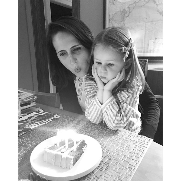 Ashley and her daughter blowing out candles on birthday cake