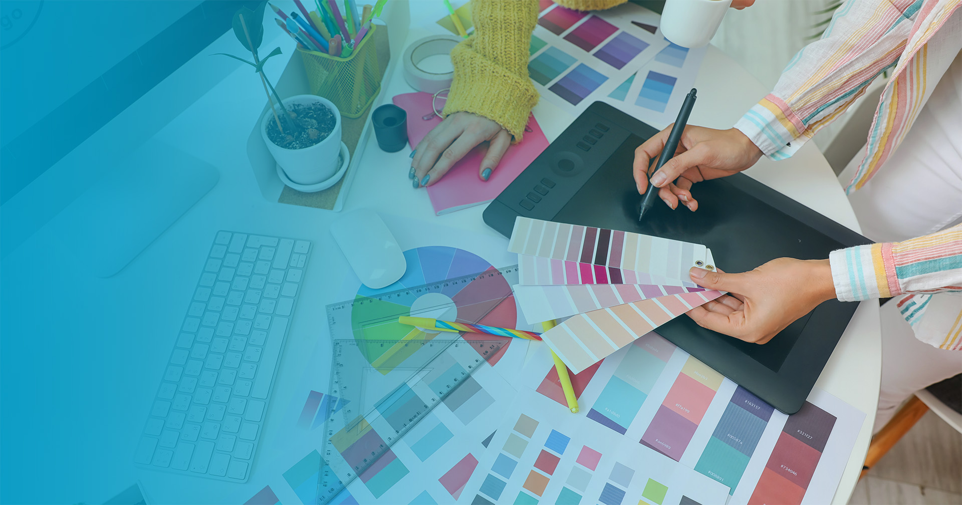 Photo from above of two people at a desk with color swatches and a drawing tablet