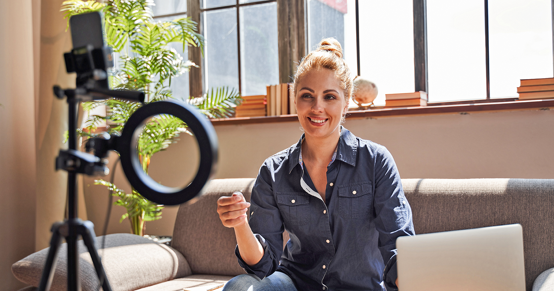 Professional woman recording a video of herself using her phone and a ring light