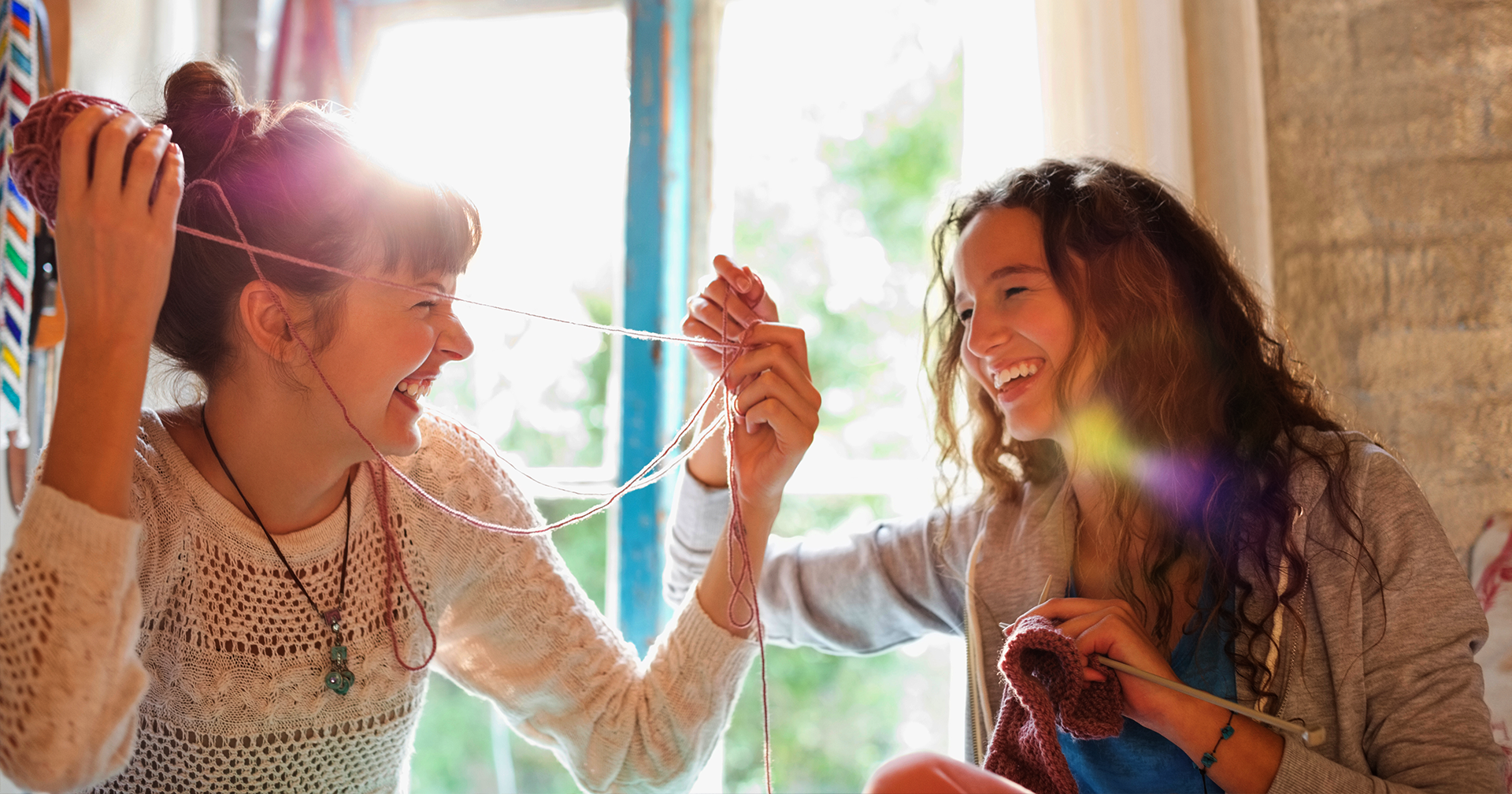 Two women holding thread