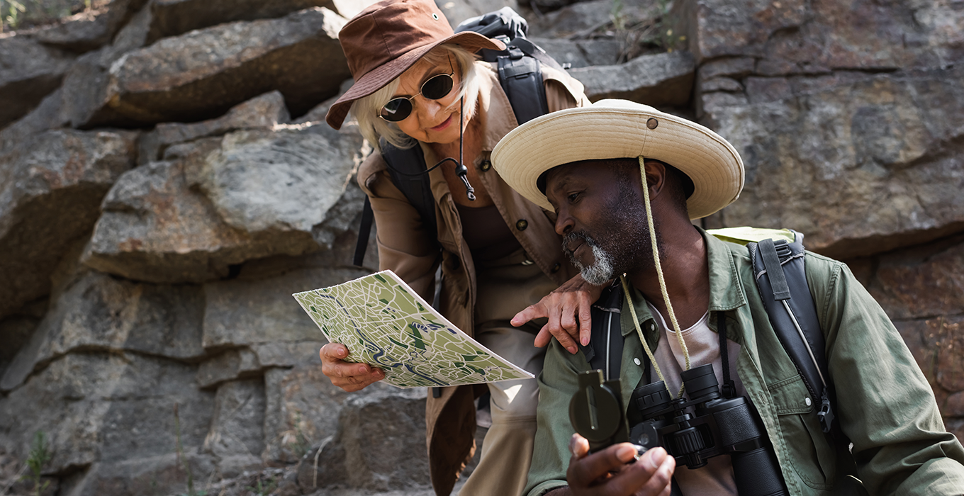 Two adults in adventure gear look at a paper map.