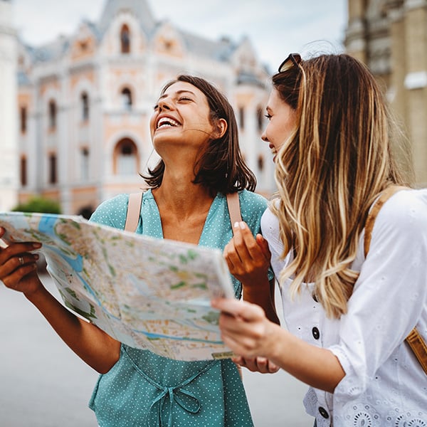 Two women laugh while looking at a paper map