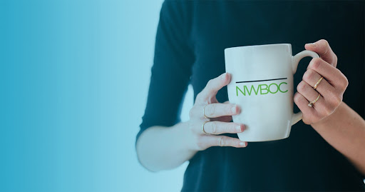 Woman holding a coffee cup with the NWBOC badge on it